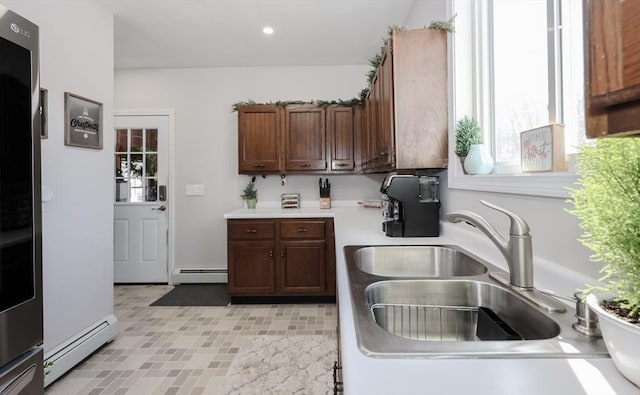 kitchen with a baseboard heating unit, recessed lighting, light countertops, and a sink