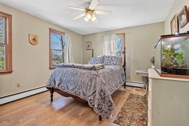 bedroom with a baseboard radiator, multiple windows, and light wood-style flooring