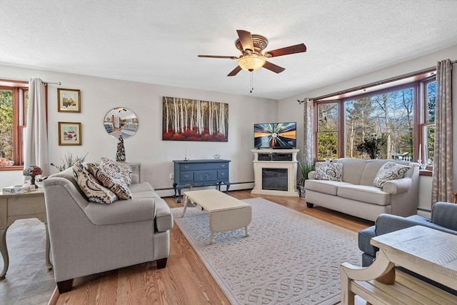 living room featuring a wealth of natural light, a glass covered fireplace, a textured ceiling, and wood finished floors