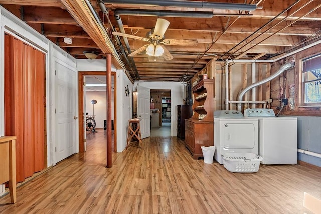 below grade area featuring washer and dryer, light wood-type flooring, and ceiling fan