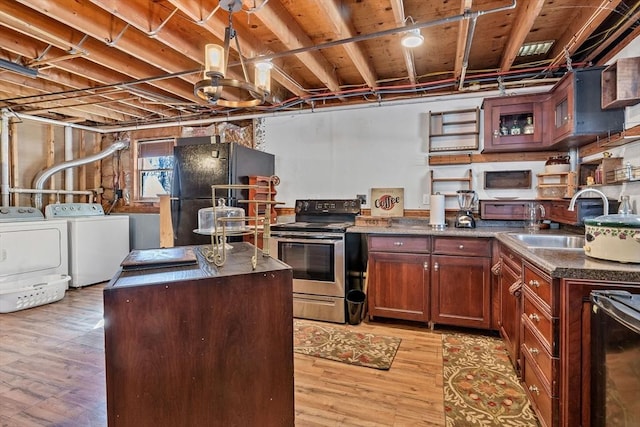 kitchen featuring electric range, a sink, dark countertops, washing machine and dryer, and freestanding refrigerator