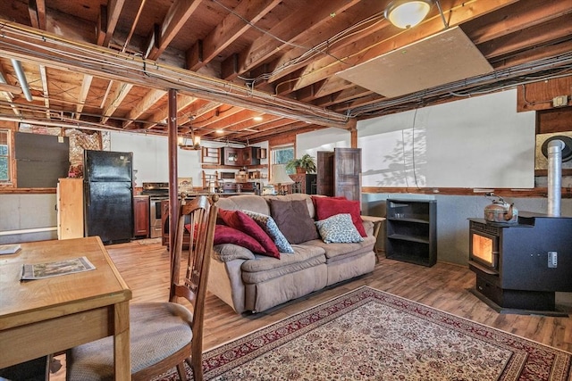 basement featuring beverage cooler, a wood stove, light wood-style floors, and freestanding refrigerator