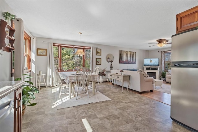 dining area with a fireplace, a textured ceiling, and a ceiling fan