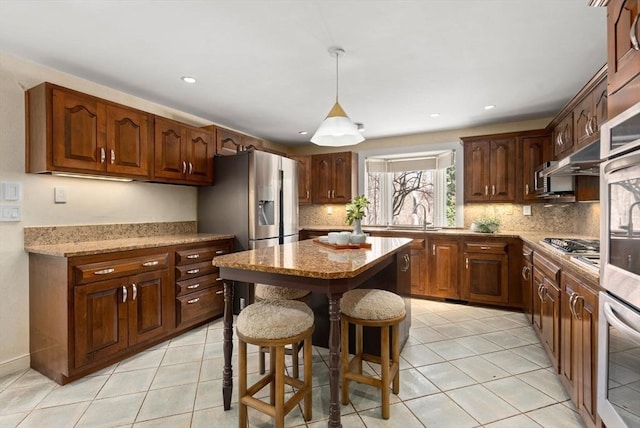 kitchen featuring light tile patterned floors, appliances with stainless steel finishes, a kitchen breakfast bar, tasteful backsplash, and a kitchen island