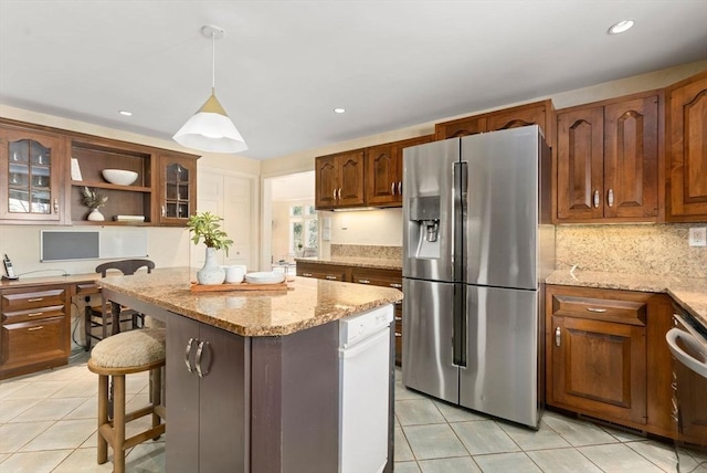 kitchen with light tile patterned flooring, stainless steel fridge, decorative backsplash, hanging light fixtures, and a center island