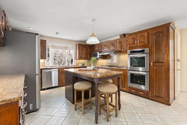 kitchen featuring a kitchen island, appliances with stainless steel finishes, sink, backsplash, and light tile patterned floors