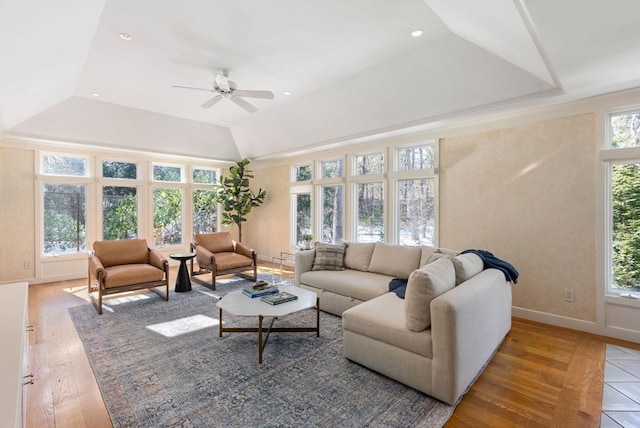 living room featuring a tray ceiling, wood-type flooring, ceiling fan, and vaulted ceiling