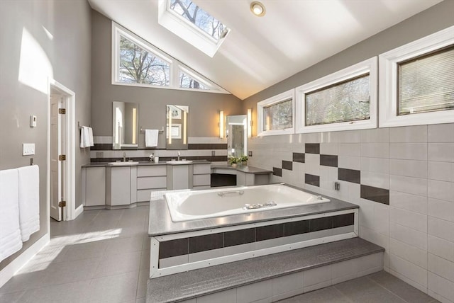 bathroom with vanity, a skylight, tile patterned floors, and tiled bath