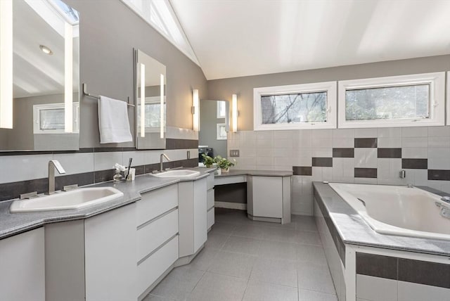 bathroom featuring tile patterned flooring, tile walls, vanity, a relaxing tiled tub, and vaulted ceiling