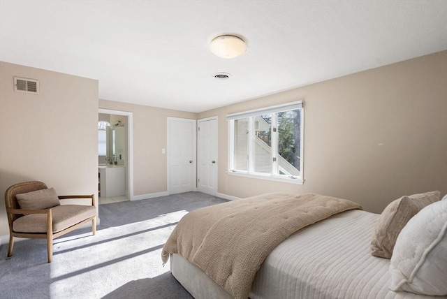 bedroom with ensuite bathroom and light carpet