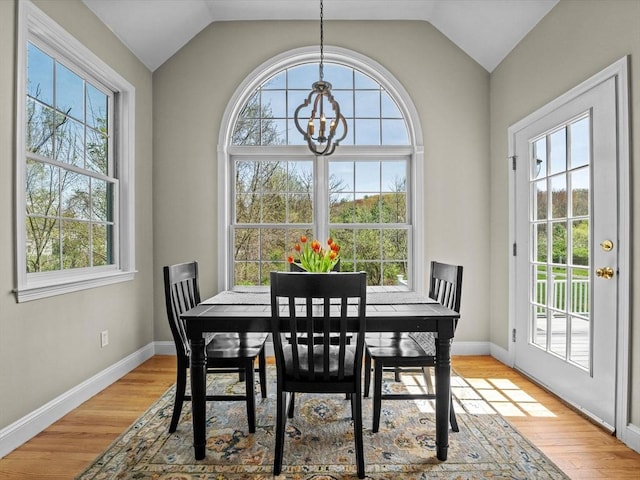 dining area featuring light wood-type flooring, lofted ceiling, and a notable chandelier