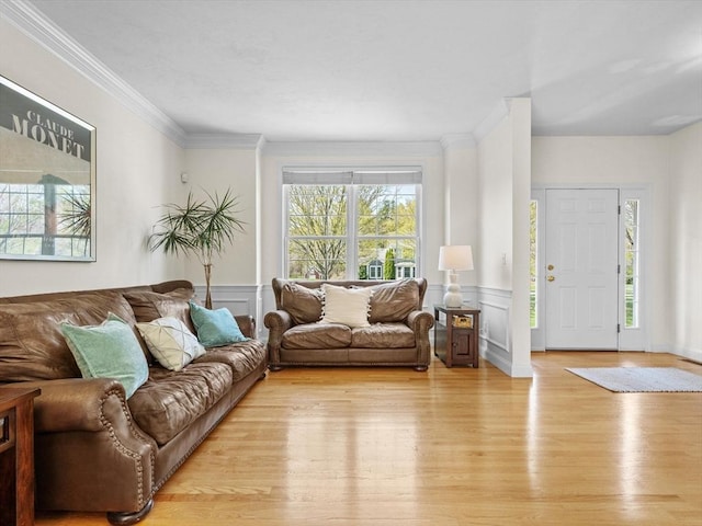 living area featuring ornamental molding, light wood-style flooring, a decorative wall, and a wainscoted wall