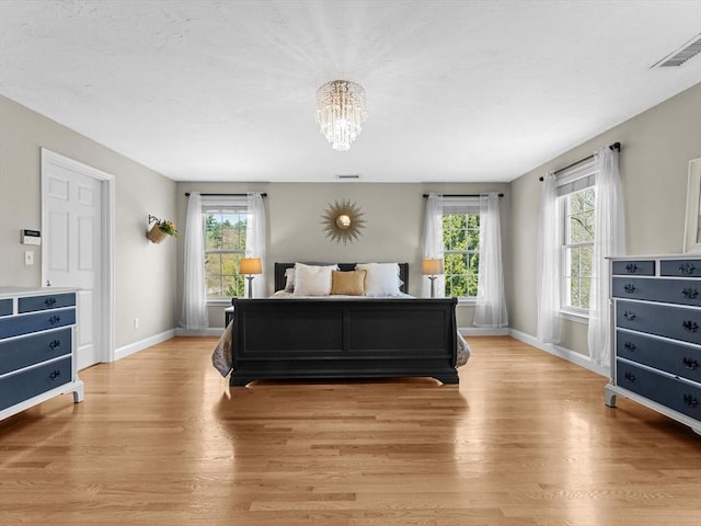 bedroom featuring an inviting chandelier, baseboards, light wood-style flooring, and visible vents