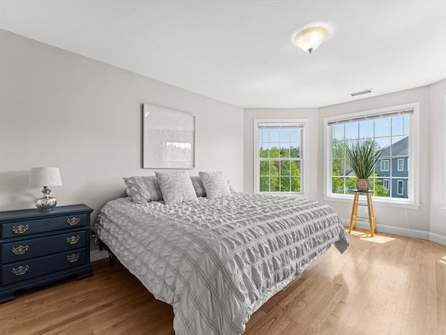 bedroom with baseboards, wood finished floors, and visible vents