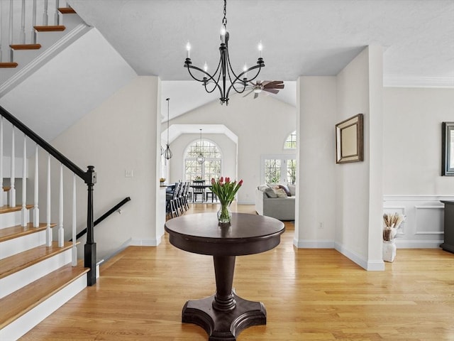 entryway featuring stairs, an inviting chandelier, vaulted ceiling, and light wood-style floors