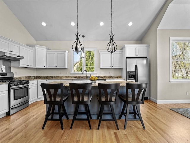 kitchen with under cabinet range hood, stainless steel appliances, vaulted ceiling, and white cabinetry