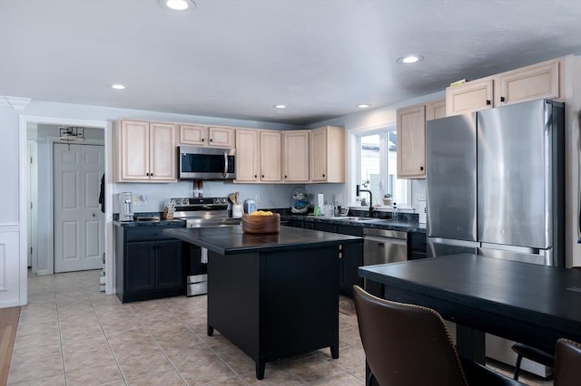 kitchen with light brown cabinetry, sink, light tile patterned floors, a kitchen island, and stainless steel appliances