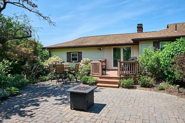 985 Tinkham Rd, Wilbraham, MA 01095 - back of property featuring a deck, a patio area, a chimney, a fire pit, and outdoor dining area