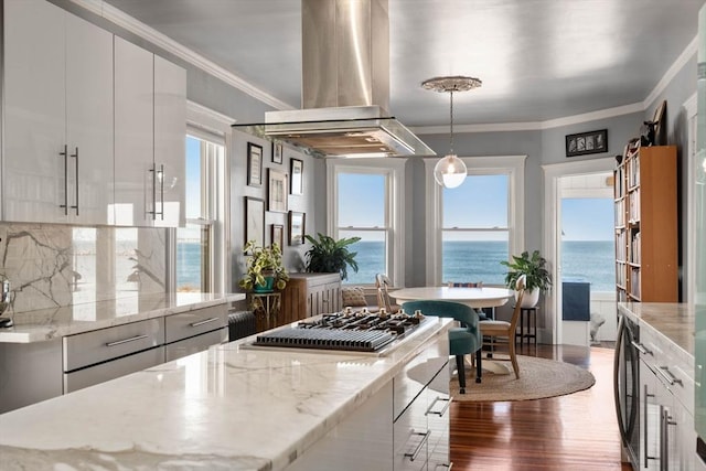 kitchen with island exhaust hood, a water view, white cabinets, and hanging light fixtures