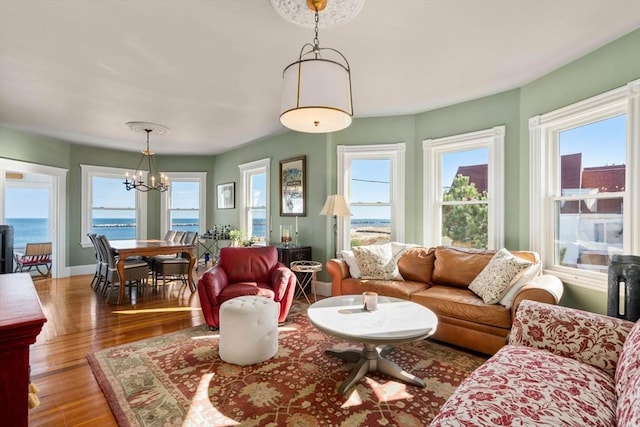 living room featuring hardwood / wood-style flooring, a healthy amount of sunlight, a water view, and a chandelier