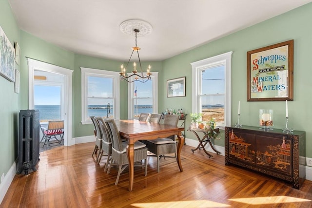 dining area featuring radiator, plenty of natural light, a water view, and an inviting chandelier