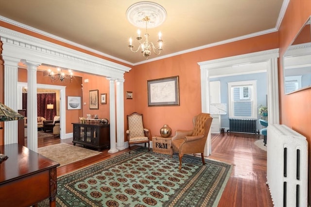 sitting room with decorative columns, radiator heating unit, and an inviting chandelier