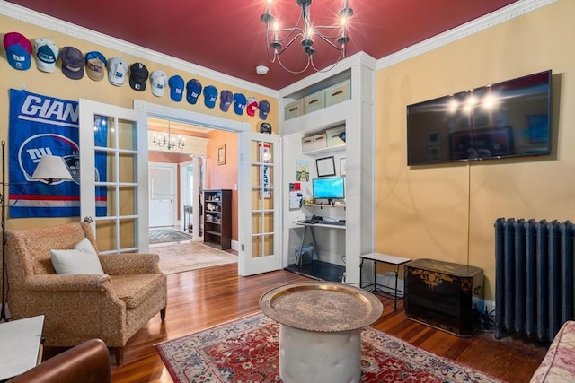 living room with hardwood / wood-style flooring, a notable chandelier, ornamental molding, and radiator