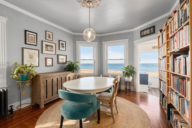 dining space with a water view, radiator heating unit, ornamental molding, and dark wood-type flooring