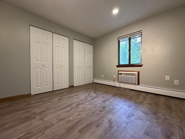 82 S Maple St Unit 44, Westfield, MA 01085 - unfurnished bedroom featuring two closets, a baseboard radiator, an AC wall unit, dark wood-type flooring, and recessed lighting