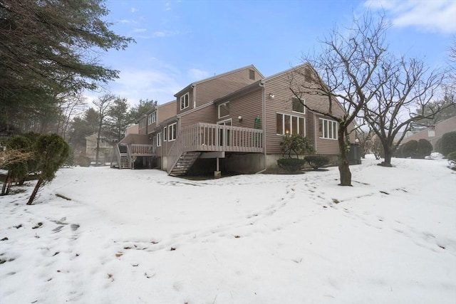 snow covered back of property featuring a wooden deck