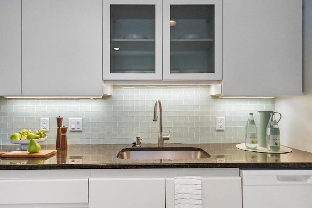 kitchen with sink, dishwasher, white cabinetry, backsplash, and dark stone counters