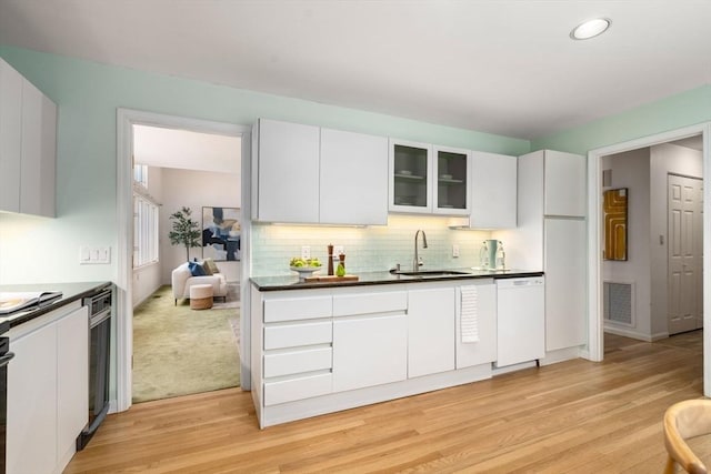 kitchen with sink, light hardwood / wood-style flooring, white dishwasher, tasteful backsplash, and white cabinets