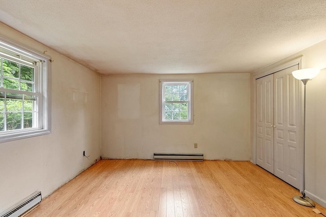 336 Otter River Rd, Templeton, MA 01468 - unfurnished bedroom featuring a baseboard radiator, a baseboard heating unit, light wood-style flooring, multiple windows, and a textured ceiling