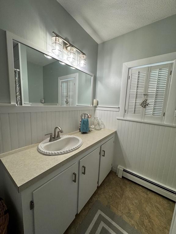 64 Edgewater Dr, Wareham, MA 02571 - full bath with vanity, wainscoting, a baseboard heating unit, and a textured ceiling