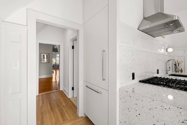 kitchen featuring white cabinetry, sink, gas stovetop, extractor fan, and light wood-type flooring