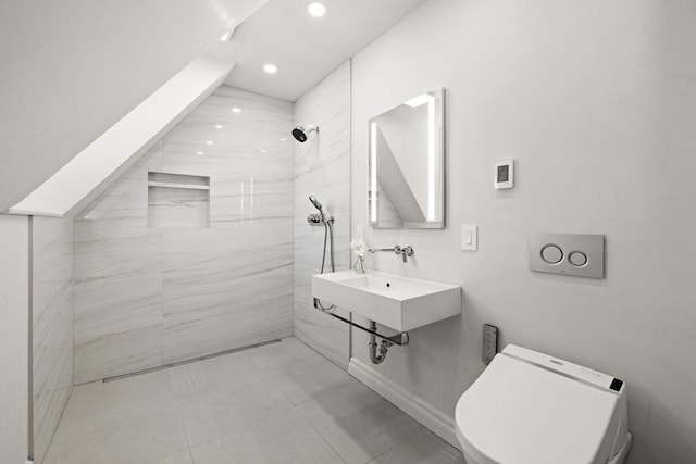 bathroom featuring a tile shower, toilet, and sink