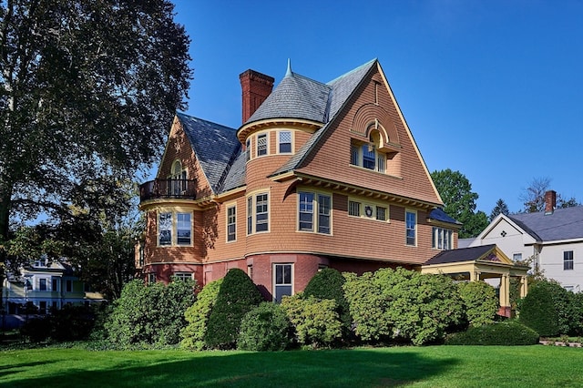 victorian home featuring a front yard and a balcony