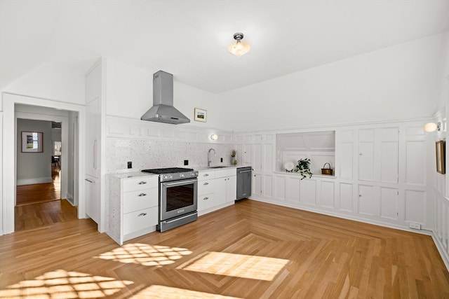 kitchen featuring white cabinets, sink, wall chimney exhaust hood, appliances with stainless steel finishes, and tasteful backsplash