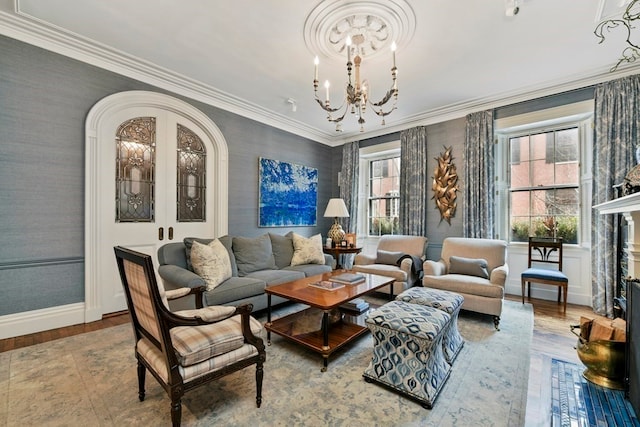 living room featuring hardwood / wood-style floors, ornamental molding, a notable chandelier, and a healthy amount of sunlight