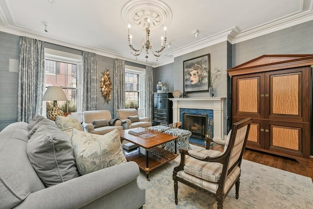 living area featuring dark hardwood / wood-style floors, a brick fireplace, ornamental molding, and a notable chandelier