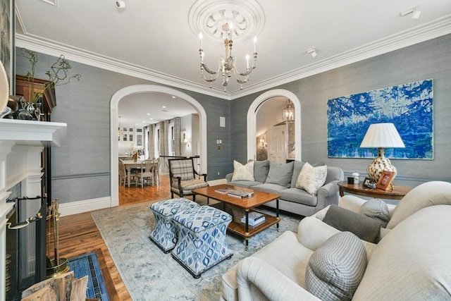 living room featuring an inviting chandelier, wood-type flooring, and ornamental molding