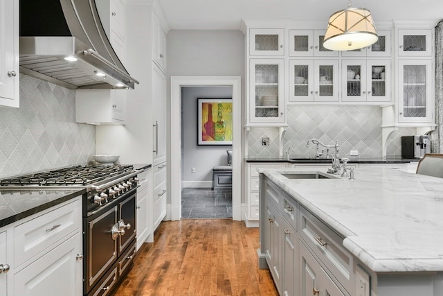 kitchen featuring hanging light fixtures, tasteful backsplash, white cabinetry, double oven range, and wall chimney exhaust hood