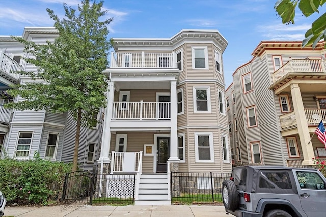 townhome / multi-family property with a balcony, covered porch, and a fenced front yard