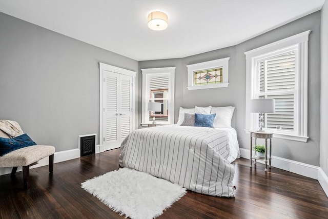 bedroom featuring a closet, wood finished floors, visible vents, and baseboards