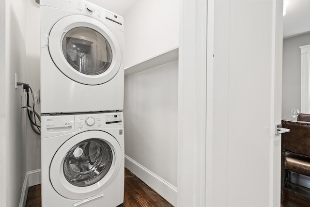 laundry room with stacked washer and dryer, laundry area, dark wood finished floors, and baseboards