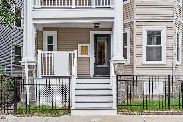 doorway to property featuring covered porch and fence