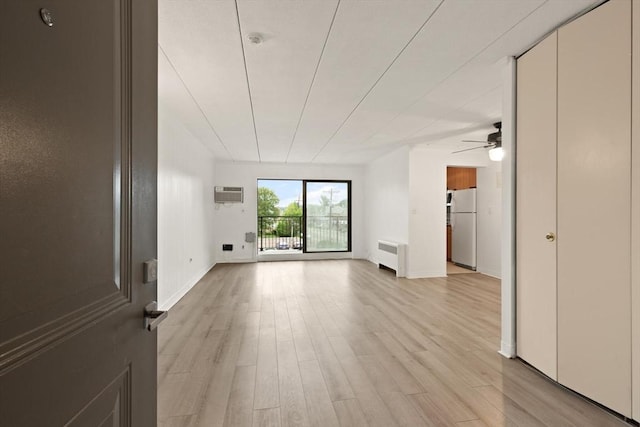 995 Massachusetts Ave Unit 301, Arlington, MA 02476 - unfurnished living room with radiator heating unit, a wall mounted air conditioner, a ceiling fan, and light wood finished floors