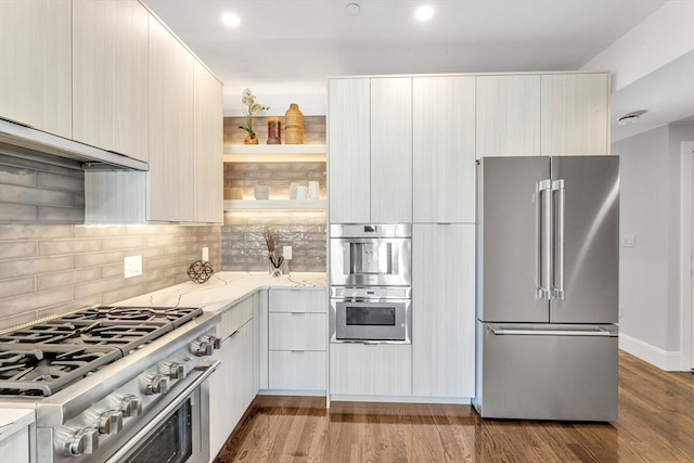 kitchen with hardwood / wood-style flooring, light stone counters, high quality appliances, and backsplash