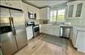 kitchen with range, stainless steel fridge with ice dispenser, and white cabinets