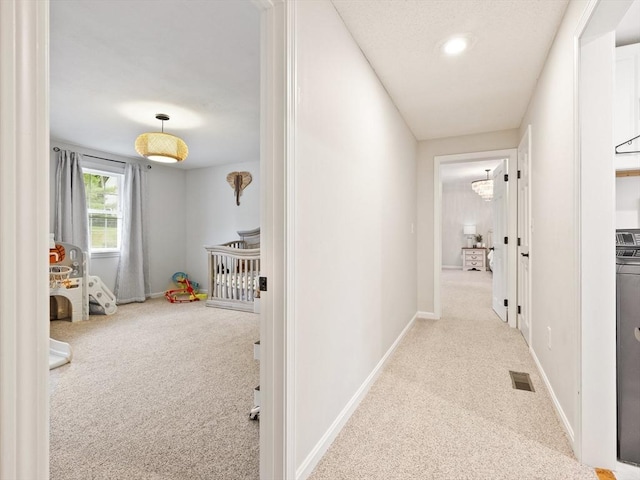 corridor with visible vents, carpet, and baseboards